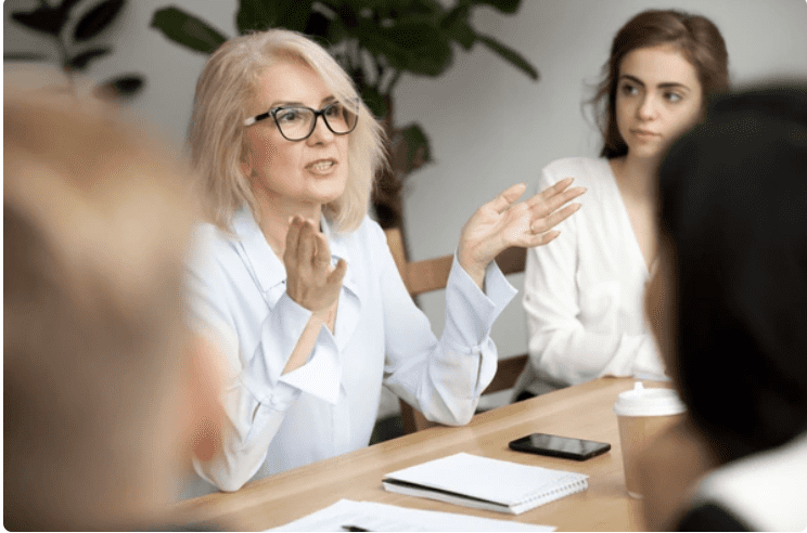 Executive sitting at a table with her hands up